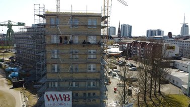Fünf Bauleute sitzen auf dem Gerüst und verfugen das Verblendmauerwerk | © Jobcenter Bremerhaven